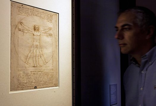 Protection contre la lumière dans les musées : un homme dans un environnement sombre regarde un objet d’exposition particulièrement sensible. 