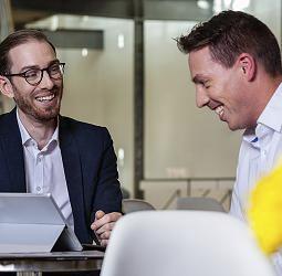 Two smiling ERCO employees discussing sustainable lighting solutions in a meeting.