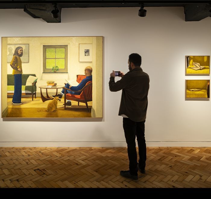 Illuminazione galleria: Visitatore fotografa opera darte con illuminazione ERCO.