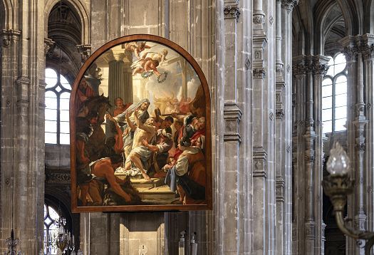 Large framed painting depicting a dramatic biblical scene, hanging on a stone column inside a grand Gothic church. The colorful artwork shows multiple figures in dynamic poses, set against an architectural background. The tall stone arches, rib vaulted ceilings, and stained glass windows of the church interior surround the painting.