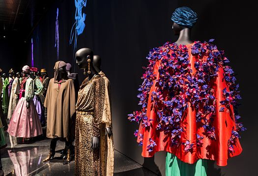 Les Åuvres maÃ®tresses du gÃ©nie crÃ©atif Yves Saint Laurent bÃ©nÃ©ficient d'une mise en lumiÃ¨re spectaculaire et d'une mise en scÃ¨ne opulente dans la salle d'exposition entiÃ¨rement noire.